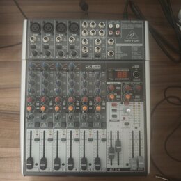 Šedý mixovací pult značky behringer s nápisem 24-BIT MULTI-FX PROCESSOR. Zařízení obsahuje několik vstupních kanálů s posuvníky, červené a modré ovlá…