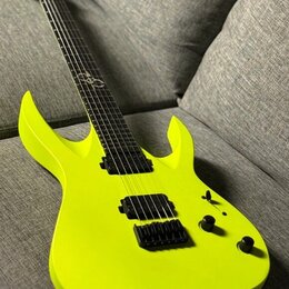 Neonově žlutá elektrická kytara s matným povrchem a výrazně vyčnívajícími rohy korpusu. Nástroj má dva černé humbuckery, černý most a dva ovládací kn…