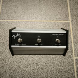 Stříbrný kytarový efektový pedál s černým rámem a vrškem z broušeného hliníku. Na levé straně je bílé logo Fender a vpravo nápis FENDER MUSICAL INSTR…