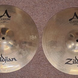 Dvě mosazné činely značky Zildjian. Levý činel nese nápisy A CUSTOM a HIHAT BOTTOM 14" 35,56 cm. Pravý činel má nápisy A CUSTOM a HIHAT TOP 14" 35,56…