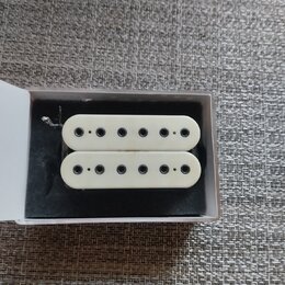 Dvě bílé humbucker snímače s šesti viditelnými póly umístěné v bílé krabičce na černém polstrování. Na snímačích nejsou žádné viditelné značky, loga…