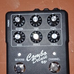 Černý kytarový předzesilovač s bílým předním panelem. Na panelu jsou šest otočných ovladačů s popisky REVERB, GAIN, LEVEL, BASS, MIDDLE a TREBLE, dva…