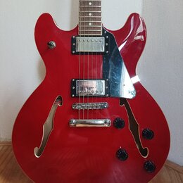 Červená polodubová elektrická kytara s hnědým hmatníkem. Nástroj má dva humbuckery s chromovanými kryty, chromovaný most a stopku. Na těle jsou čtyři…
