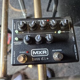 Černý kytarový pedál s nápisy MXR a bass d.i.+ . Zařízení obsahuje pět otočných potenciometrů s popisky BASS, MID, TREBLE, GAIN a GATE, dva zapínací…