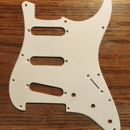 Bílá pickguard pro elektrickou kytaru s třemi výřezy pro snímače. Je vyrobena z plastového materiálu a obsahuje otvory pro šrouby a ovládací prvky. N…