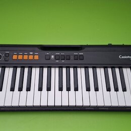 Černý elektronický klavír s bílými a černými klávesami. Na levé straně je bílé logo CASIO a na pravé straně nápis CasioTone CT-S100. V horní části se…