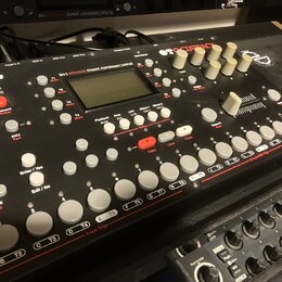 Šedý sampler s nápisy Elektron a OCTATRACK. Na horní části je displej a text DYNAMIC PERFORMANCE SAMPLER. Zařízení obsahuje bílé ovratové tlačítka, č…