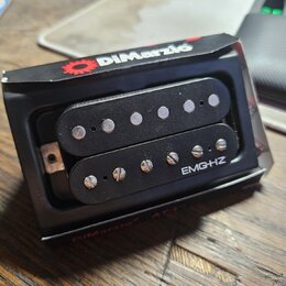 Černý humbucker s dvěma řadami snímačů umístěný v originálním černém obalu. Na spodní části je bílý nápis EMG-HZ a na horní hraně obalu červené logo…