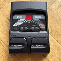 Černý kytarový procesor s nápisy RP 55 a MODELING GUITAR PROCESSOR. Zařízení obsahuje červený digitální displej, několik ovládacích tlačítek a dva pe…