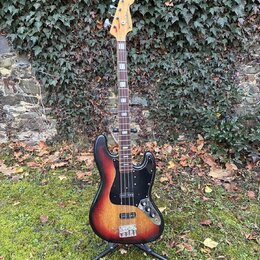 Elektrická basová kytara s korpusem v červeno-žlutém sunburst provedení a černým pickguardem. Na hlavě hmatníku je vidět nápis „Westminster“. Nástroj…