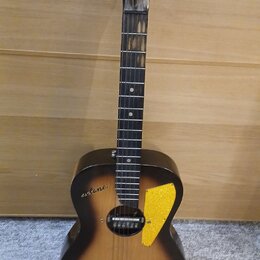 Akustická kytara s tmavým, přechodovým povrchem (sunburst). Na hlavě je bílý nápis CABALLERO a na korpusu vlevo od otvoru nápis astano. Nástroj má žl…