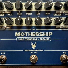 Modrý rackový efekt s nápisy MOTHERSHIP a TUBE OVERDRIVE - PREAMP. Na spodní části je logo s hlavou zvířete a text TsakalisAudioWorks CH 1/2. Zařízen…