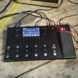 Černý kytarový procesor s displejem a řadou spínačů. Na displeji je vidět nápis G1A Evo a v dolní části text 1. Electro Harmonix Drive. Zařízení má č…