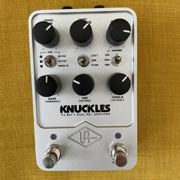 Stříbrný kytarový pedál s nápisem KNUCKLES a pod ním textem '92 REV F DUAL REC AMPLIFIER. Na horní části jsou tři černé otočné ovladače s popisky [RO…