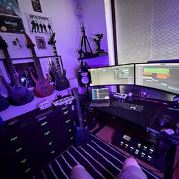 Fotografie zachycuje hudební studio s několika elektrickými kytarami. Na stěně jsou zavěšeny čtyři kytary, z nichž tři jsou černé a jedna červená; na…