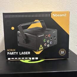 Fotografie znázorňuje kartónové balení laserového efektu. Na krabici je zobrazen černý přístroj s rukojetí a nápisy beamZ, ACRUX a PARTY LASER. V pra…