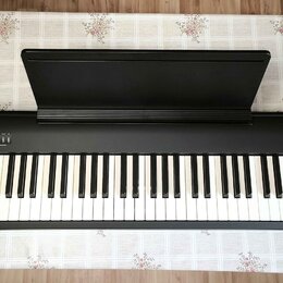 Černý digitální piano s bílými a černými klávesami a přiloženým notovým pultem. V pravém horním rohu je bílý nápis Roland FP30. V levé části horního…