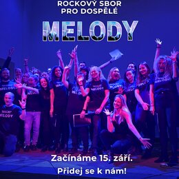 Fotografie zobrazuje skupinu lidí v černých tričkách s bílým nápisem „ROCKOVÝ SBOR PRO DOSPĚLÉ MELODY“. Snímek je pořízen v interiéru s výrazným modr…