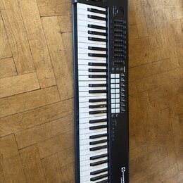 Černý MIDI kontrolér s klaviaturou. Na pravé straně je umístěno několik řad tlačítek, osm otočných potenciometrů a v horní části dva posuvníky. V pra…
