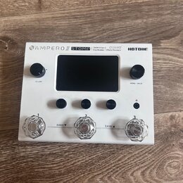 Bílý efektový procesor Hotone Ampero Stomp. Na horní hraně je nápis AMPERO STOMP, CDCM HD Gen 2 Amp Modeler / Effects Processor a logo HOTONE. Zaříze…