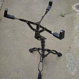 Černý skládací stojan na noty z kovového materiálu. Stojan má trojnožku a rozkládací horní část s opěrnými rameny. Na povrchu nejsou viditelné žádné…