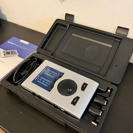 Stříbrné audio rozhraní v černém plastovém kufru spolu s kabelem a několika adaptéry. Na zařízení je nápis Babyface Pro FS a popisky vstupů a výstupů…