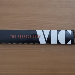 Dvě dřevěné bubenícké paličky s bílými špičkami, které jsou spojené originálním papírovým páskem. Na pásku je uveden nápis THE PERFECT PAIR® a logo V…