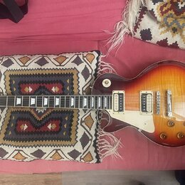 Elektrická kytara s trupem ve tvaru singlecut a barevným přechodem od žluté k tmavě hnědé (sunburst). Na hlavě je viditelné logo "Epiphone". Nástroj…