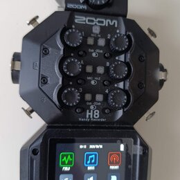 Černý digitální záznamový systém ZOOM H8 Handy Recorder. Zařízení má v horní části čtyři ovratové ovládací knoflíky s popisky MIC IN 1, 2, 3 a 4 a ná…