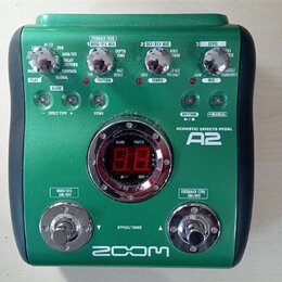 Zelený efektový pedál s nápisem ACOUSTIC EFFECTS PEDAL A2 a logem ZOOM v dolní části. Zařízení obsahuje několik otočných potenciometrů, červené kontr…