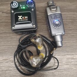 Černý přijímač s nápisy Xvive a U4 RECEIVER, vybavený dvěma ovladačovacími knoflíky a kontrolkami. Vedle něj je stříbrný bezdrátový vysílač s tlačítk…