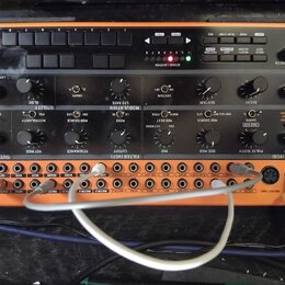 Oranžový analogový syntetizátor s černým ovládacím panelem. Na pravé straně je nápis CRAVE a v levém horním rohu logo behringer. Přístroj obsahuje řa…