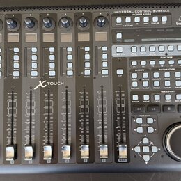 Černá kontrolní plocha s nápisem UNIVERSAL CONTROL SURFACE ENCOVER ROSSIGN a logem behringer. Zařízení obsahuje osm posuvníků, řadu tlačítek s různým…