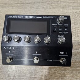 Černý kytarový procesor s nápisem BOSS GT-1000CORE GUITAR EFFECTS PROCESSOR. Zařízení má digitální displej, šest kovových otočných ovladačů s čísly 1…