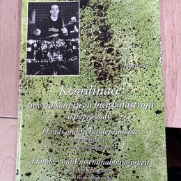 Fotografie znázorňuje obal učebnice s názvem „Koordinace hry na soupravu bicích nástrojů a doprovody“. Pod hlavním názvem jsou uvedeny překlady „Hand…