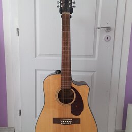 Akustická kytara s vyřezem v korpusu, světlým dřevem desky a tmavým hmatníkem. Na hlavě je viditelné logo Fender. Nástroj má neobvyklý počet ladiček…