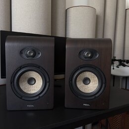 Dva studiové monitory v tmavě hnědém dřevěném provedení s rounded hranami. Každý reproduktor má v horní části výšek s černou mřížkou a ve spodní část…