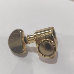 Zlatý ladicí mechanismus s kovovým povrchem. Na těle mechanismu je vyryt nápis GROVER. Povrch vykazuje mírné známky opotřebení a znečištění.