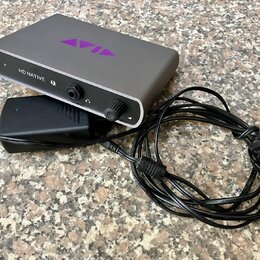 Šedý audio interface s nápisem HD NATIVE a fialovým logem AVID na horní straně. Zařízení má na předním panelu tlačítko, ovrtací knoflík a svítící kon…