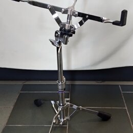 Chromovaný stojan na noty s černými plastovými úchvaty a černou deskou. Na spodní části teleskopické nohy je viditelný nápis YAMAHA. Stojan stojí na…