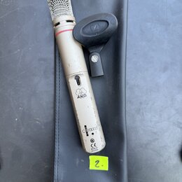 Kondenzátorový mikrofon stříbrné barvy s kovovou síťkou v horní části a červeným prstenem pod ní. Na těle je viditelné logo AKG, nápis C1000 S a ozna…