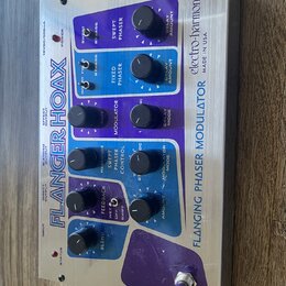Kovový efekt pedál s nápisy FLANGER HOAX a electro-harmonix MADE IN USA. Zařízení má modré a fialové ovládací panely s několika černými otočnými knof…