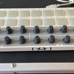 Bílý MIDI kontrolér s názvy Arturia a BEATSTEP Controller & Sequencer. Zařízení obsahuje dvě řady bílých čtvercových padů, 16 černých otočných knoflí…