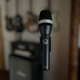 Černý dynamický mikrofon s mřížkou a bílým prstenem v horní části. Na těle je viditelné logo AKG a nápis D 5. Povrch mikrofonu je matný a v dobrém st…