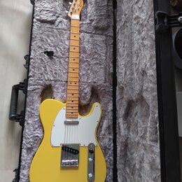 Žlutá elektrická kytara typu Telecaster s bílým pickguardem a javorovým hmatníkem v černém polstrovaném kufru. Na hlavě nástroje je viditelné logo Fe…
