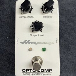 Bílý efekt pedál s třemi černými otočnými knoflíky, označenými jako Compression, Release a Output Level. Na spodní části je nápis OPTO COMP a Analog…