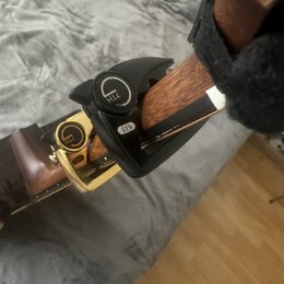 Na hrazdici dřevěného nástroje je upevněno černé plastové příslušenství. Na horní části je viditelné logo ve tvaru stylizovaného písmene G a nápis ZT…