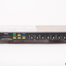 Černý rackový efektový procesor s nápisem HARMONICS/DELAY HD 1000. Na předním panelu je logo Ibanez, digitální displej a několik barevných tlačítek s…