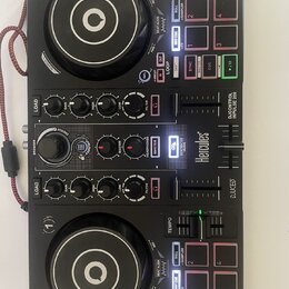 Černý DJ kontrolér s dvěma jog-koly a centrální sekcí s knoflíky a posuvníky. Na přístroji jsou viditelné nápisy Hercules, DJCONTROL IMPULSE 200 a DJ…