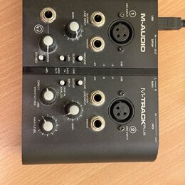 Černý zvukový interface M-AUDIO M-TRACK PLUS. Zařízení má dva identické vstupní kanály s popisky MIC INPUT (1 a 2), GUITAR/LINE INPUT, INSERT a ovlad…